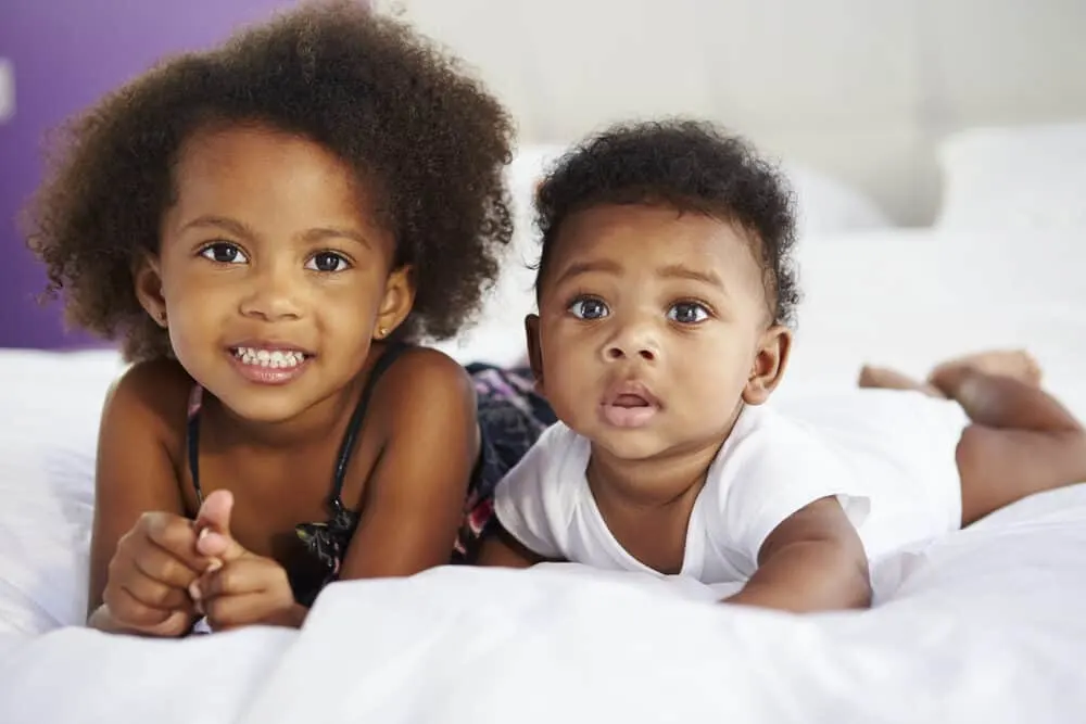 Baby Hair on Ultrasound vs When Born: When Can You Tell? 8 Two cute kids that are sisters posing for a photo as their mommy take the picture in the background.