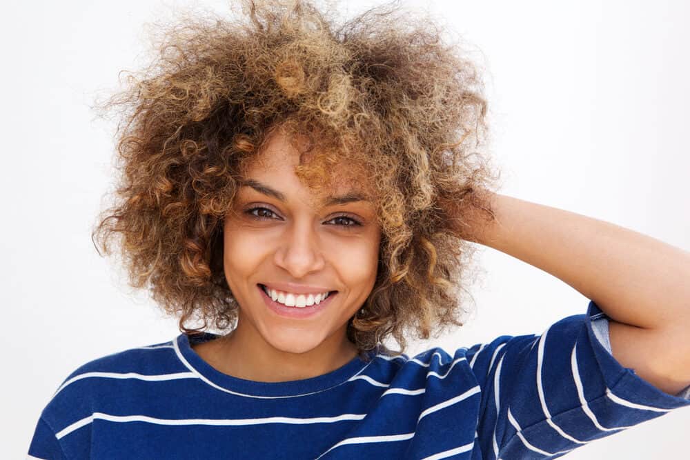 Cute young African American female with dark brown hair with highlights styled with natural oils.