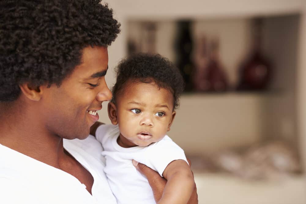 Dad cuddles his first baby daughter and admires that she's born with a full head of hair and at a normal weight. 