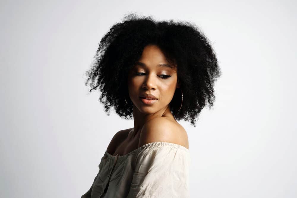 Black female showing off her natural curls after using the Vegamour hair serum to support hair growth.