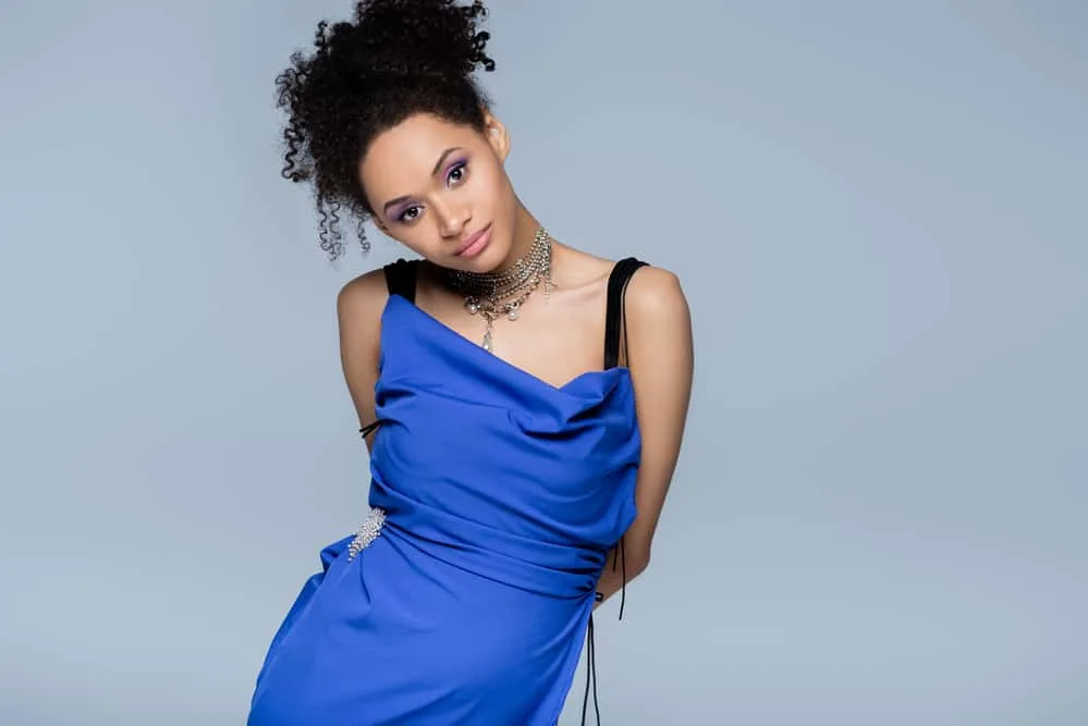 Should You Do Hair or Makeup First When Getting Ready? 6 Confident African American female dressed for an early ceremony time with hair clips specifically holding her updo.