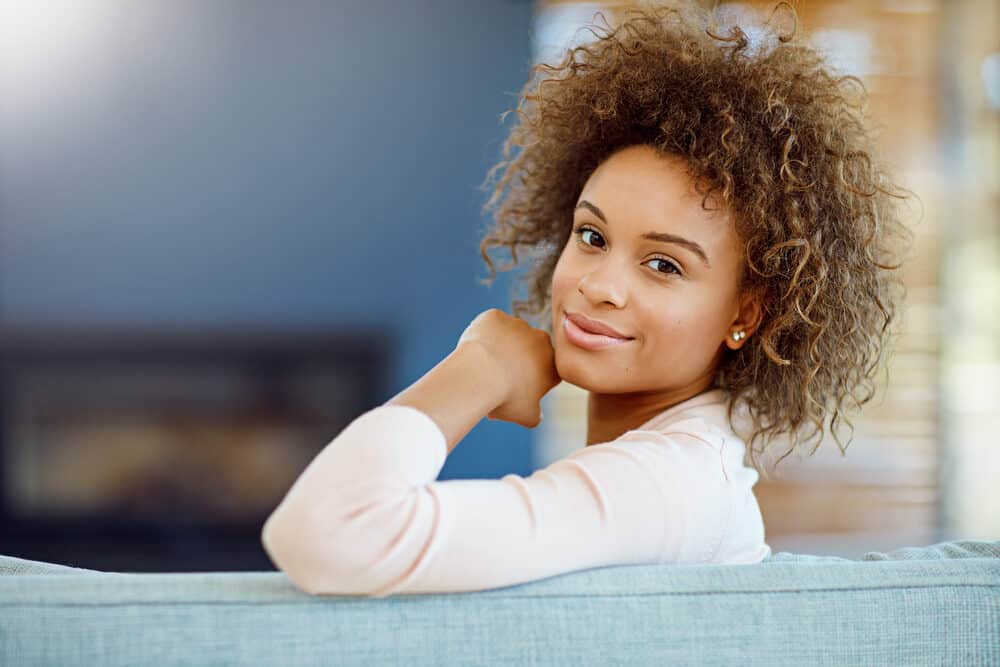 Cute black with a great smile wearing diamond earrings and dark brown balayage no-lift hair color.