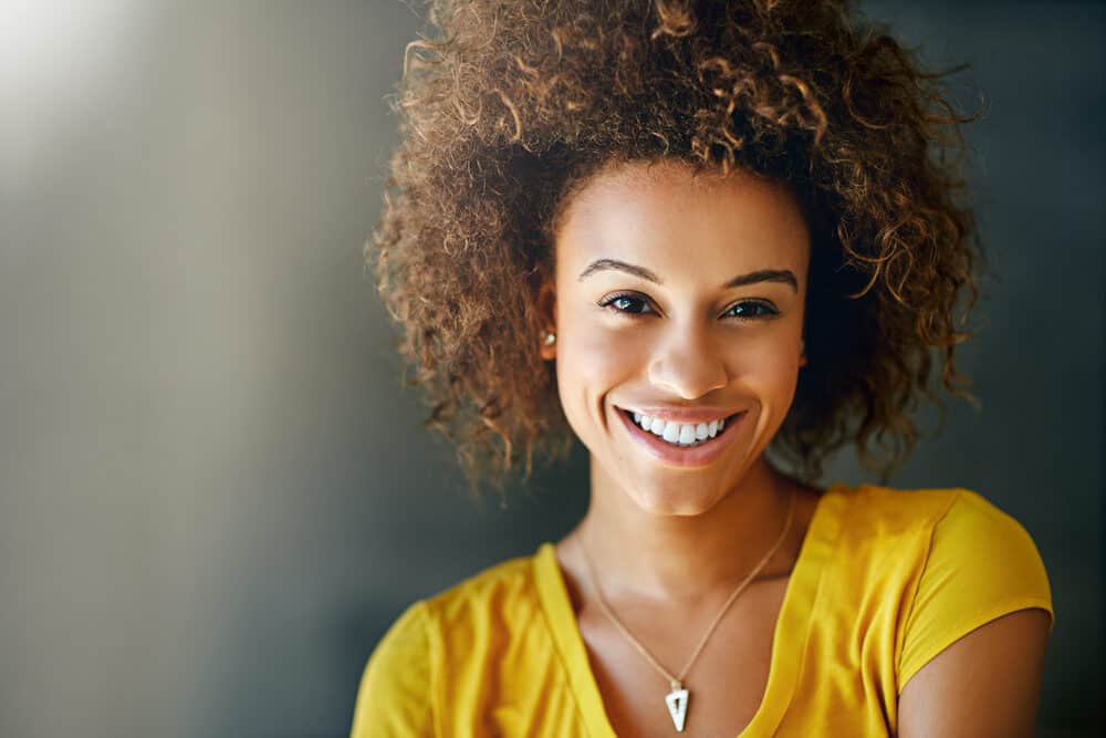 Cute African American female with a light brown hair color with undertones created with dark brown dye.