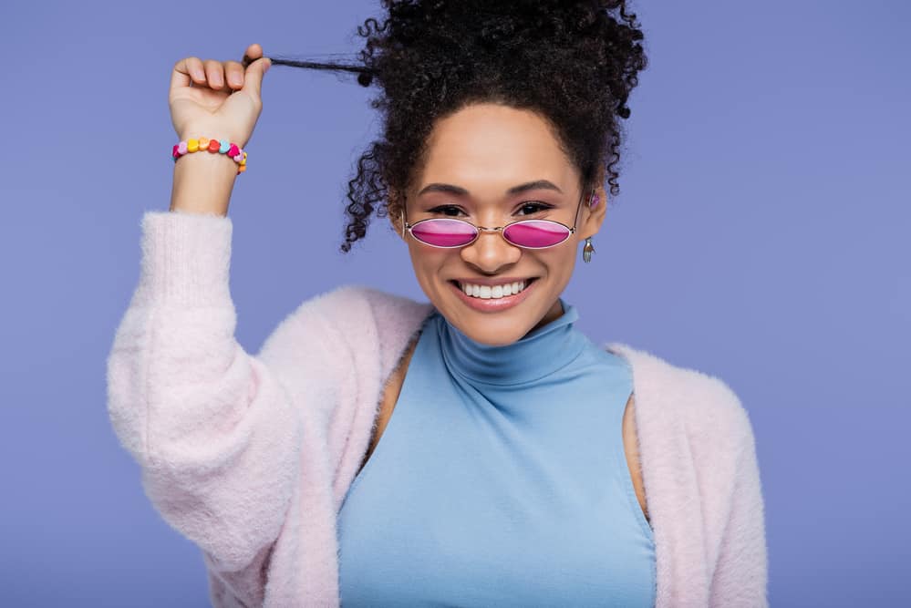 Cute black female with healthy hair showing her curly hair type and oily roots wearing pink eyeglasses.