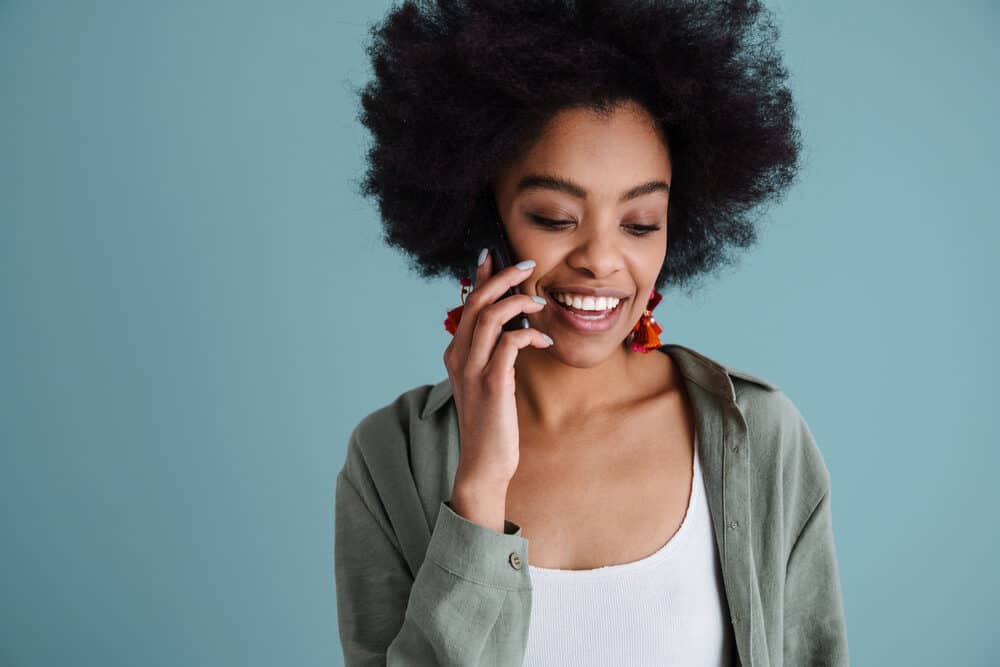 Attractive mixed race black female with long hair wearing green fingernail polish, a green shirt, and a white t-shirt.