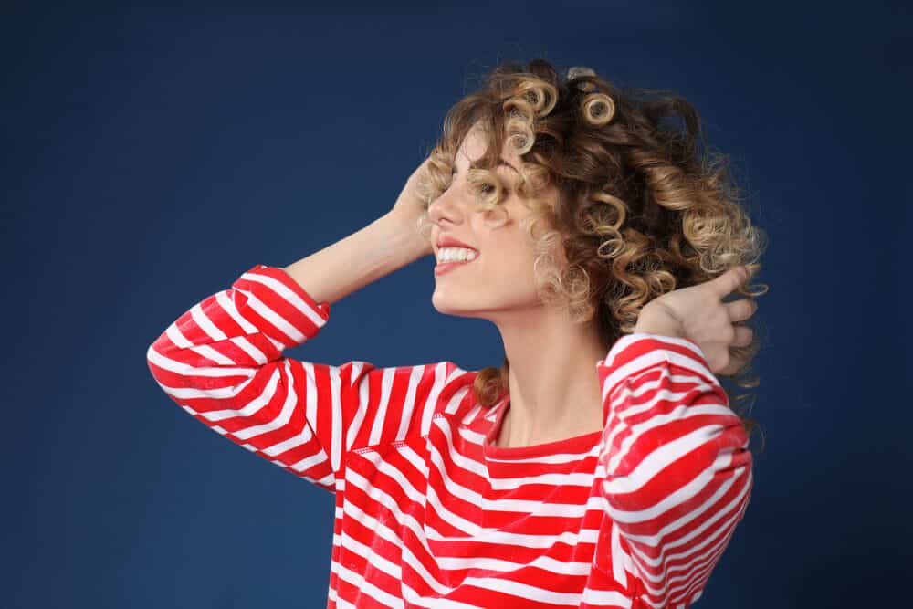 Cute white woman with permanent curls wearing a red and white shirt with subtle blonde highlights.