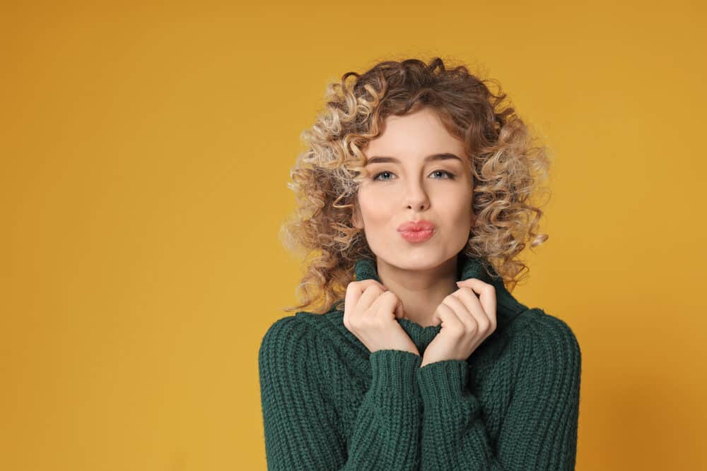 Cute white girl with green eyes and pink lips wearing wavy hair permed using a professional hairstylist. 