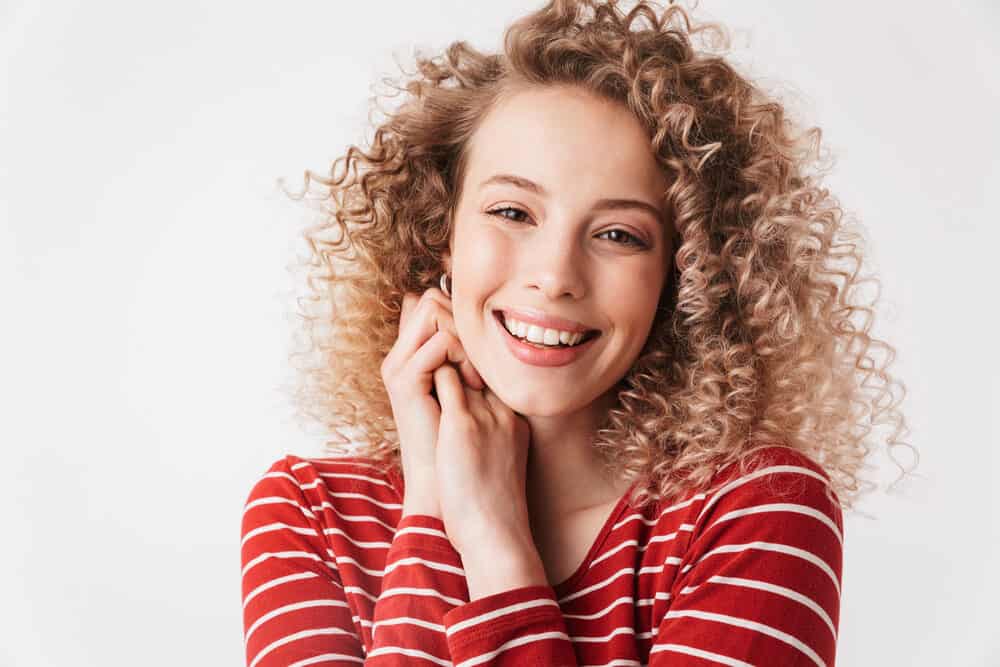 Cute Caucasian female with 3A loose curls on newly permed hair wearing a red and white shirt.