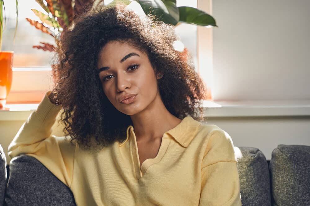 Beautiful African American female whose brittle hair feels like straw after an inadequate hair care routine.