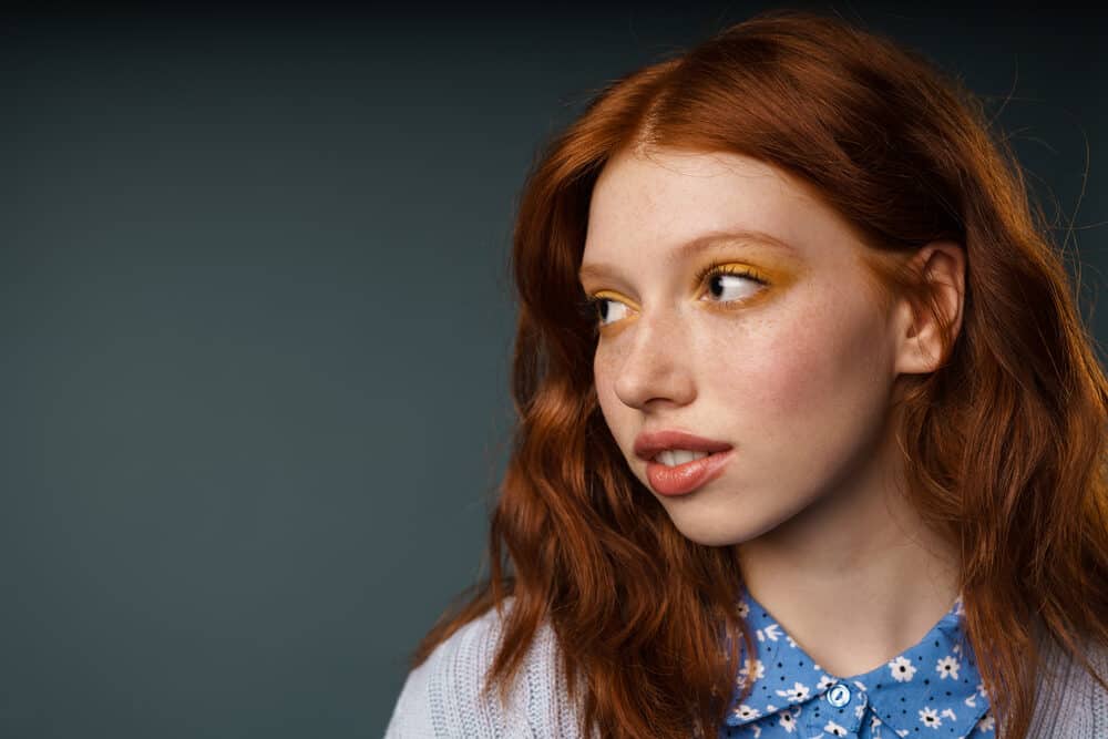 Cute young white woman with 1C hair freshly colored with an orange dye after using bleach to lighten her dark hair.