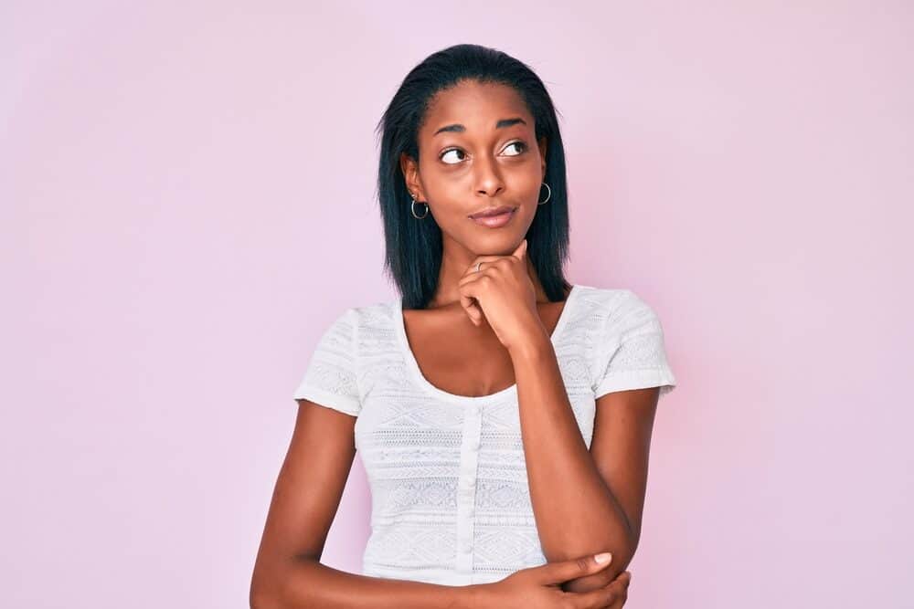 Young African American lady enjoying her hair's natural moisture after using a heat protectant spray to style her curls.