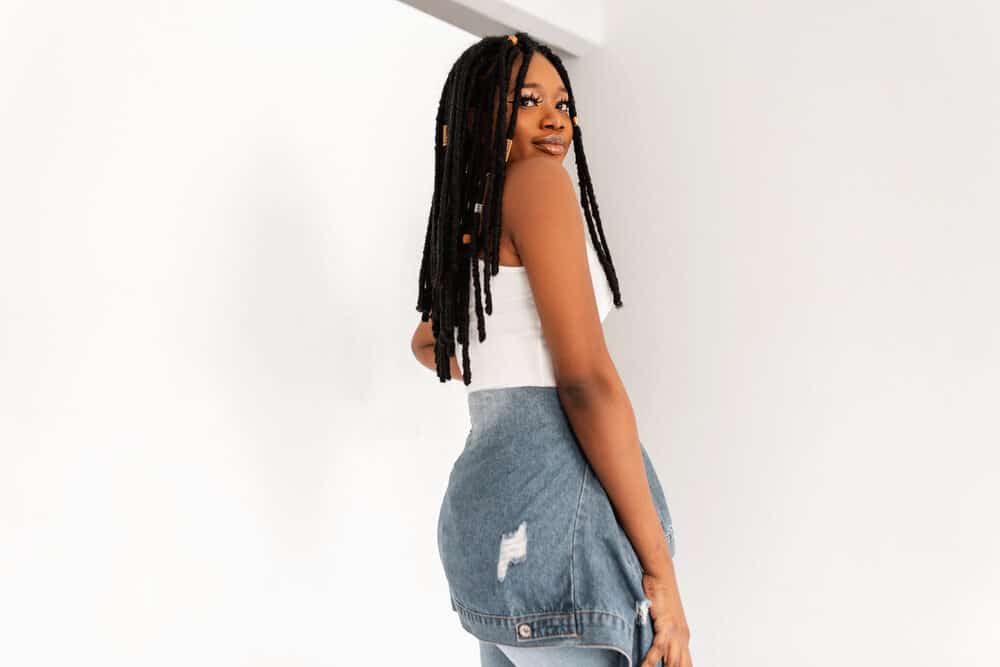 Trendy African American woman with dreadlocks wearing a casual denim outfit.
