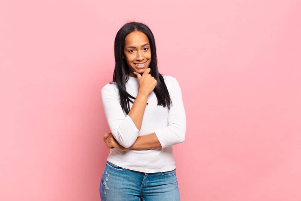 Light-skinned female with healthy hair  styled with a paddle brush wearing a casual white shirt and torn blue jeans.