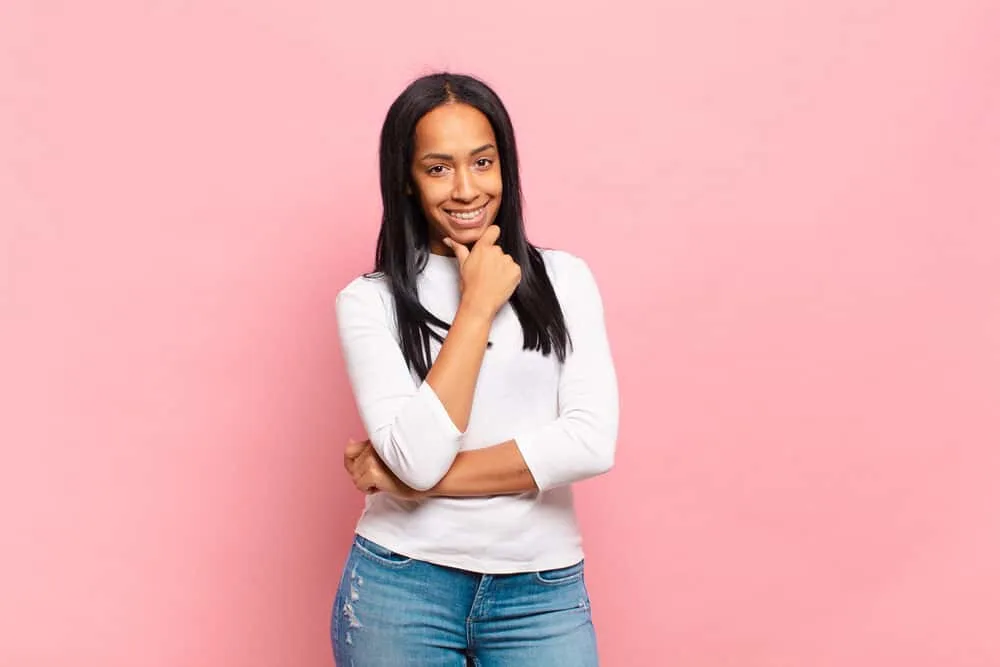 Can You Use Hairspray Before Straightening Your Hair? 5 Light-skinned female with healthy hair styled with a paddle brush wearing a casual white shirt and torn blue jeans.