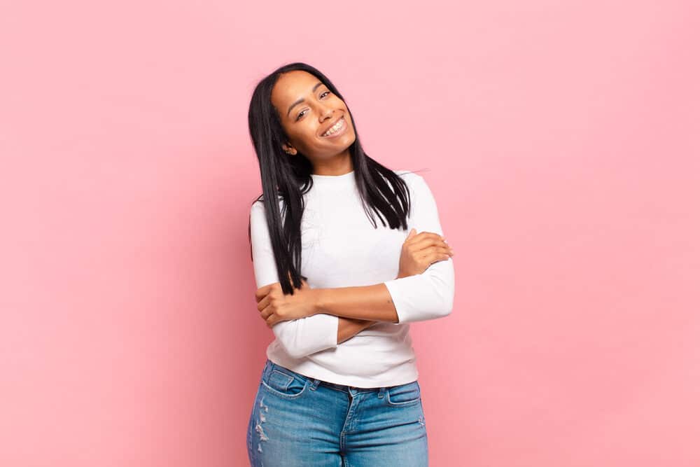 Lady with straight locks that recently used a flat iron on her damp hair wearing a white shirt and blue jeans.