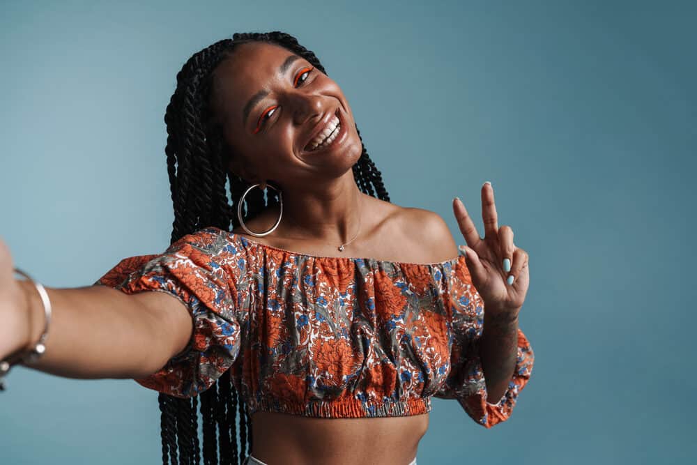 Young African American lady keeping her hair clean by using an ACV cleanser to spray braids directly.