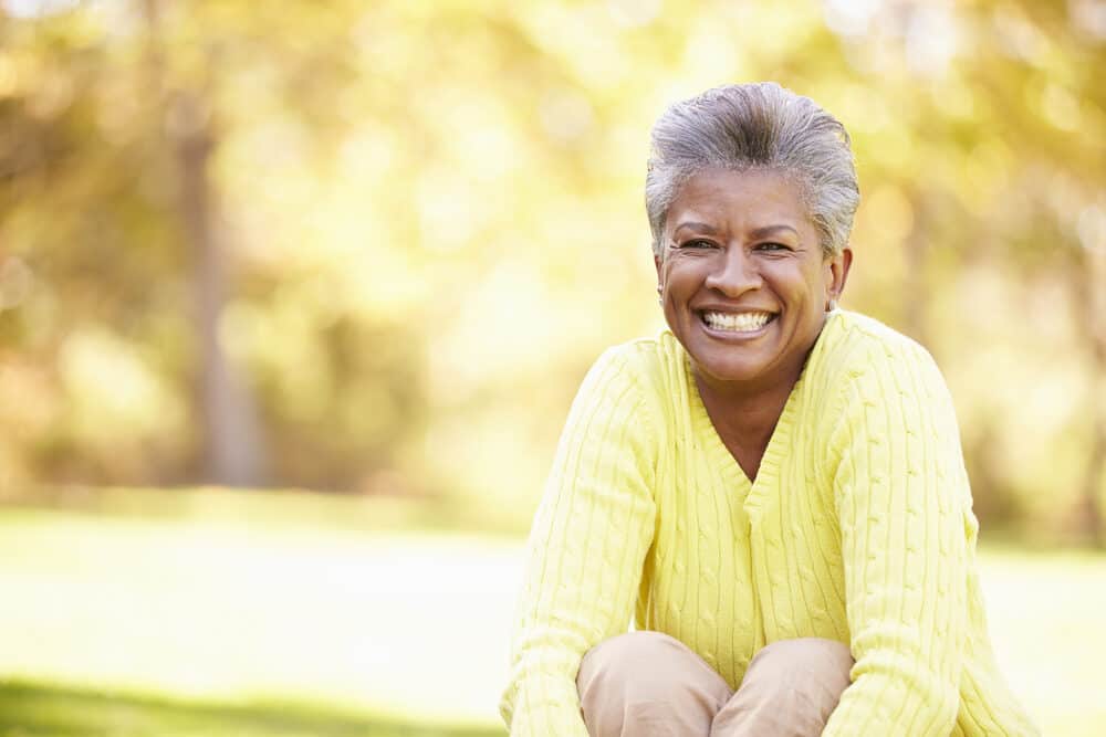 Mature African American female with mostly grey hair with a few dark hairs in the middle wearing a yellow sweater.