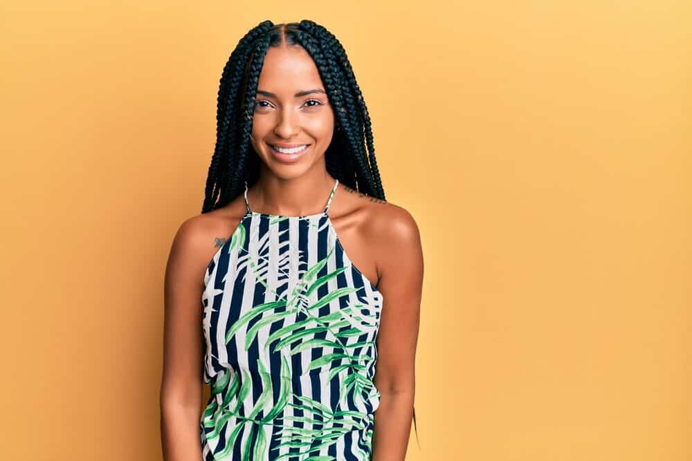 Cute Hispanic woman wearing box braids that keeps her scalp hydrated and hair healthy with braid spray.