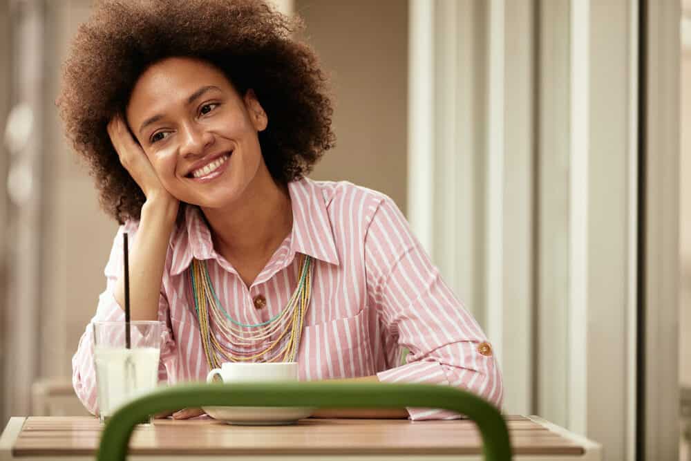 Gorgeous woman with a dark brown cool hair color having a warm cup of tea at a local shop in Birmingham, Alabama.