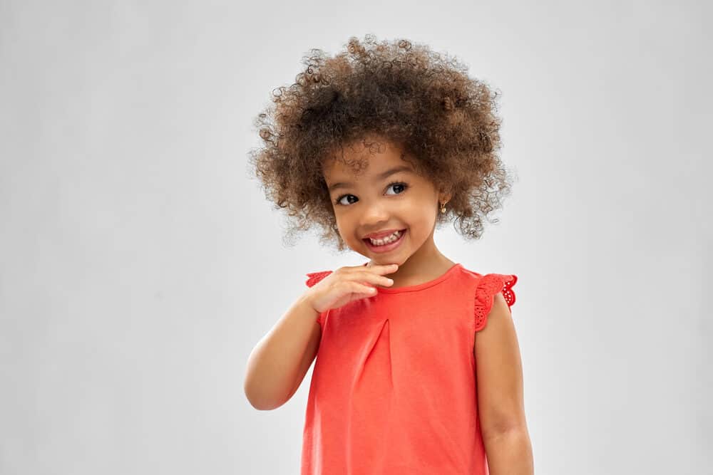 African American toddler smiling after drinking breast milk from a paper cup.