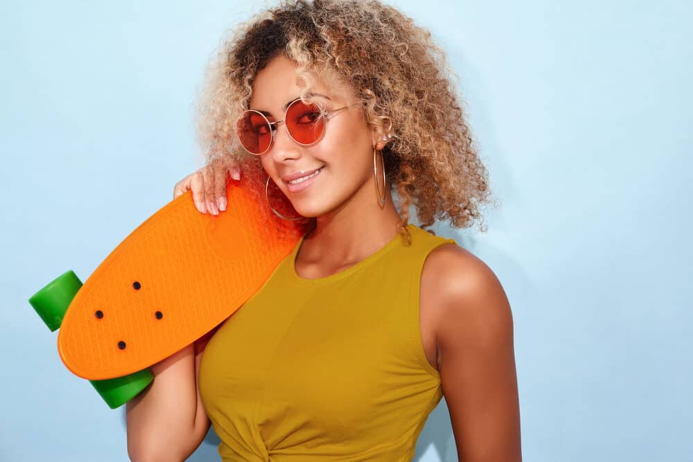 Cute African American female with dark brown hair with orange tones wearing rose-colored glasses.