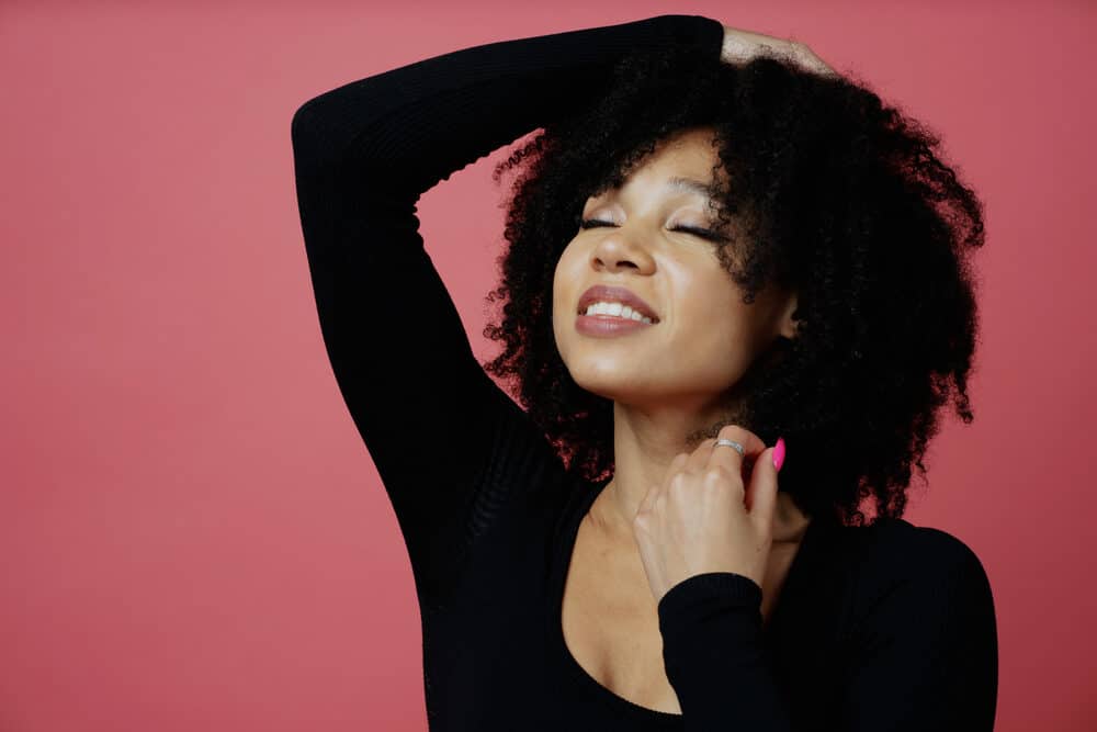 Woman with her eyes closed holding a hair strand in her left hand and rubbing her fine hair with her right hand.