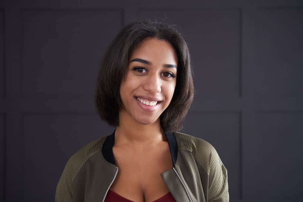 African American woman wearing straight hair styled with coconut hair oil and stylish green jacket.