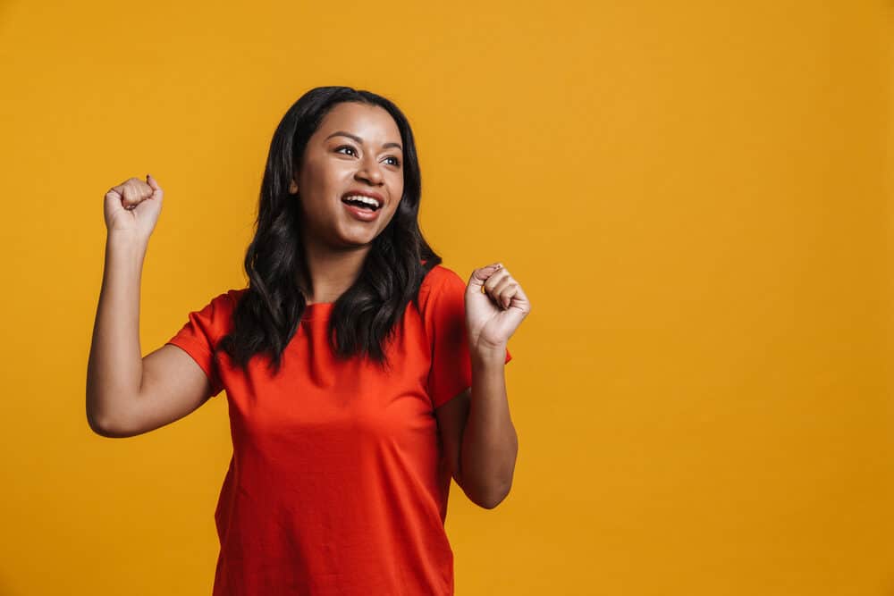 Cute adult female wearing a red t-shirt showing off her jet black hair shaft color after drying her wet hair.