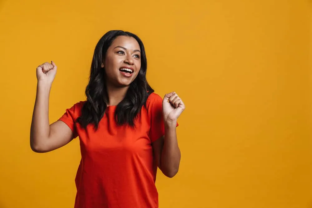 Can You Flat Iron Your Hair After Dyeing It? Should You Wait? 8 Cute adult female wearing a red t-shirt showing off her jet black hair shaft color after drying her wet hair.