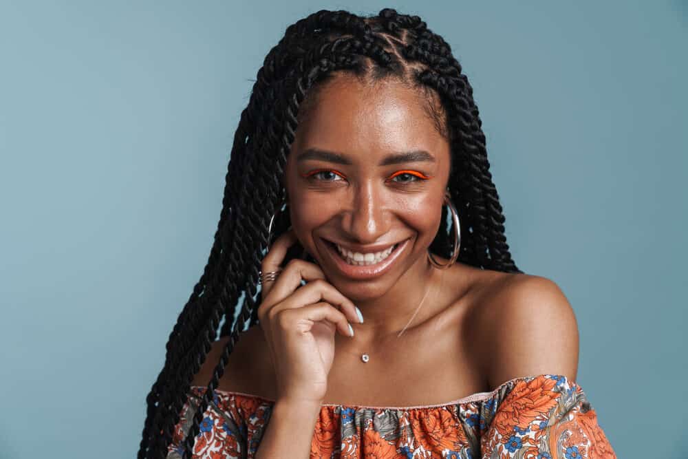 Young African female with a detailed braided protective style that looks fresh after using an oil shine mist.