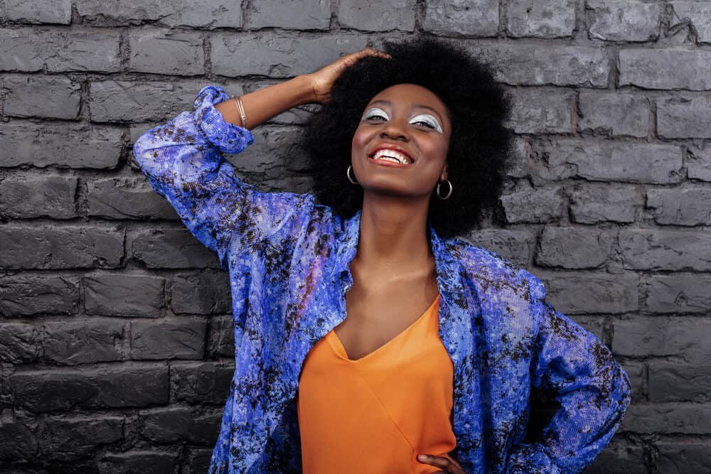 Amazing makeup. Dark-haired beautiful model with big earrings smiling brightly while posing for the photo