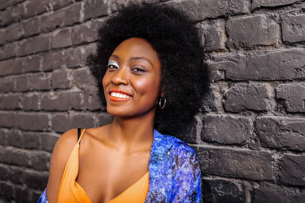 Pretty African American female with healthy natural hair strands wearing an afro hairstyle on a kinky hair type.