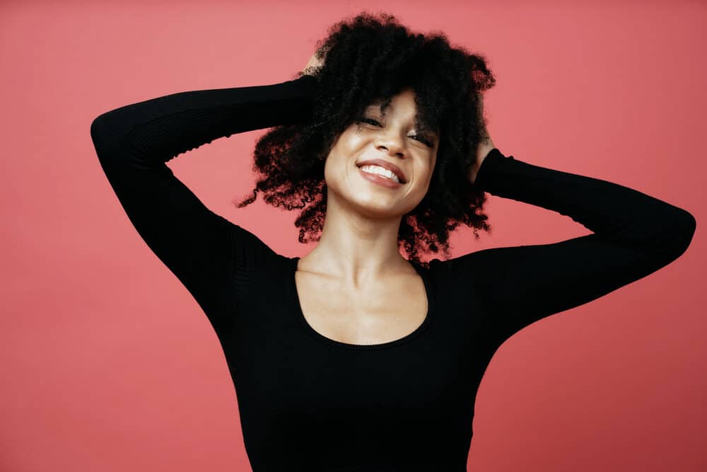 Lady with a big smile admiring her curls after during the Squish to Condish method encouraging hair health.