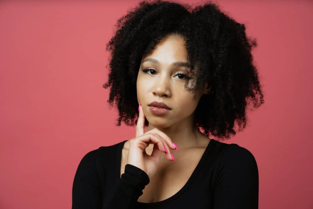 Curious African American woman with a dark brown hair color wearing a wash and go style.