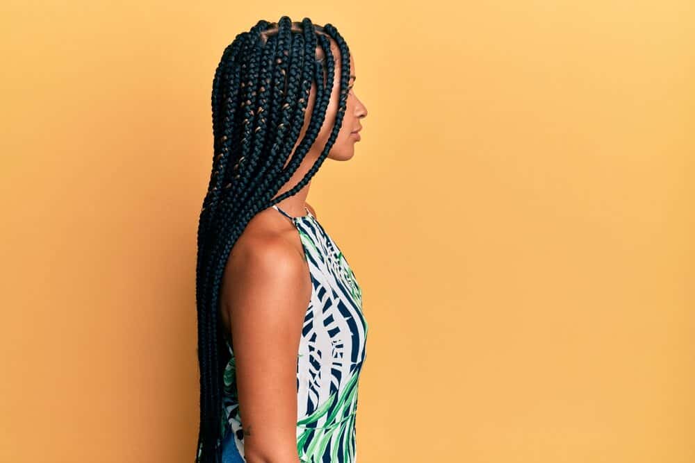 A confident woman with a fresh braided hairstyle has her baby hair ("edged") styled nicely with lavender oil.