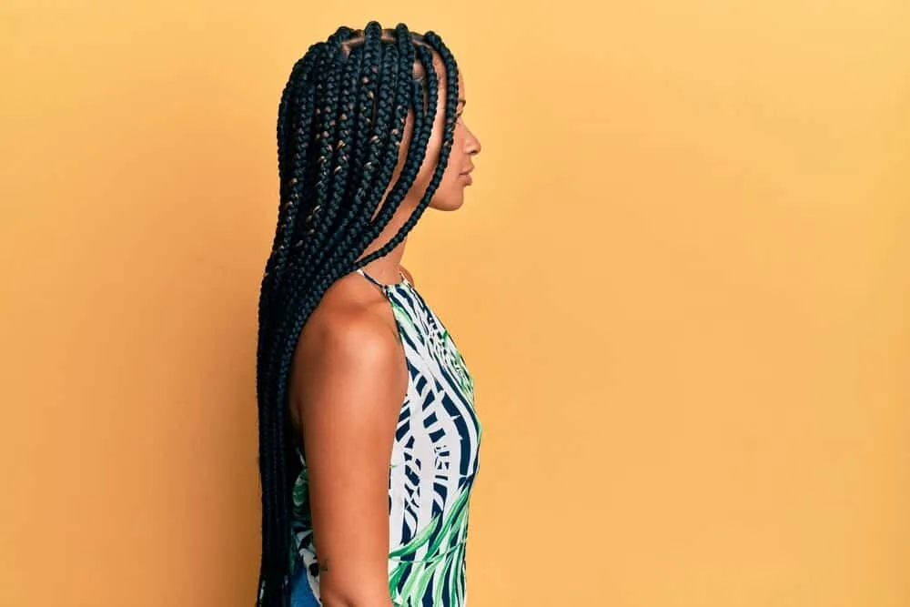 A confident woman with a fresh braided hairstyle has her baby hair ("edged") styled nicely with lavender oil.