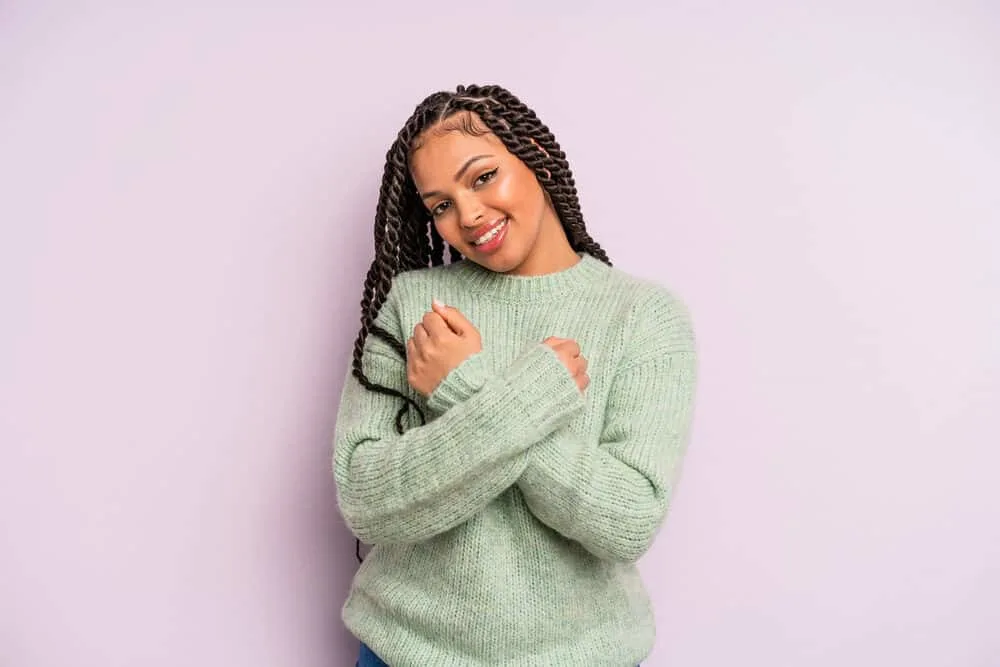 Young light-skinned Latina female wearing a stylish look with Mexican braids and a green knitted sweater.