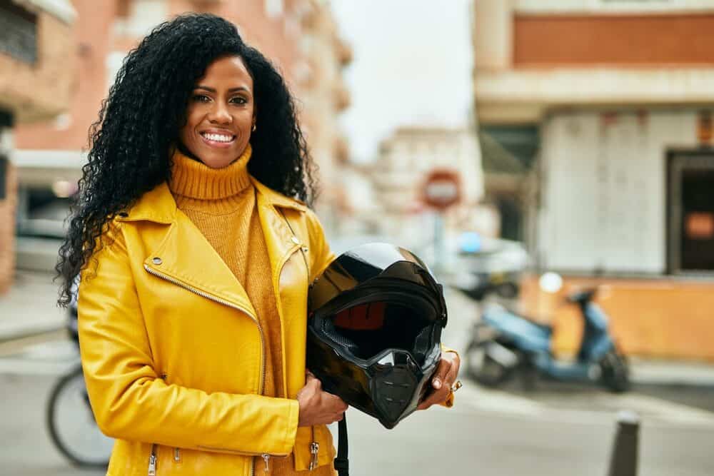 Beautiful black lady holding a motorcycle helmet wearing her 4C natural hair under a lace front wig.