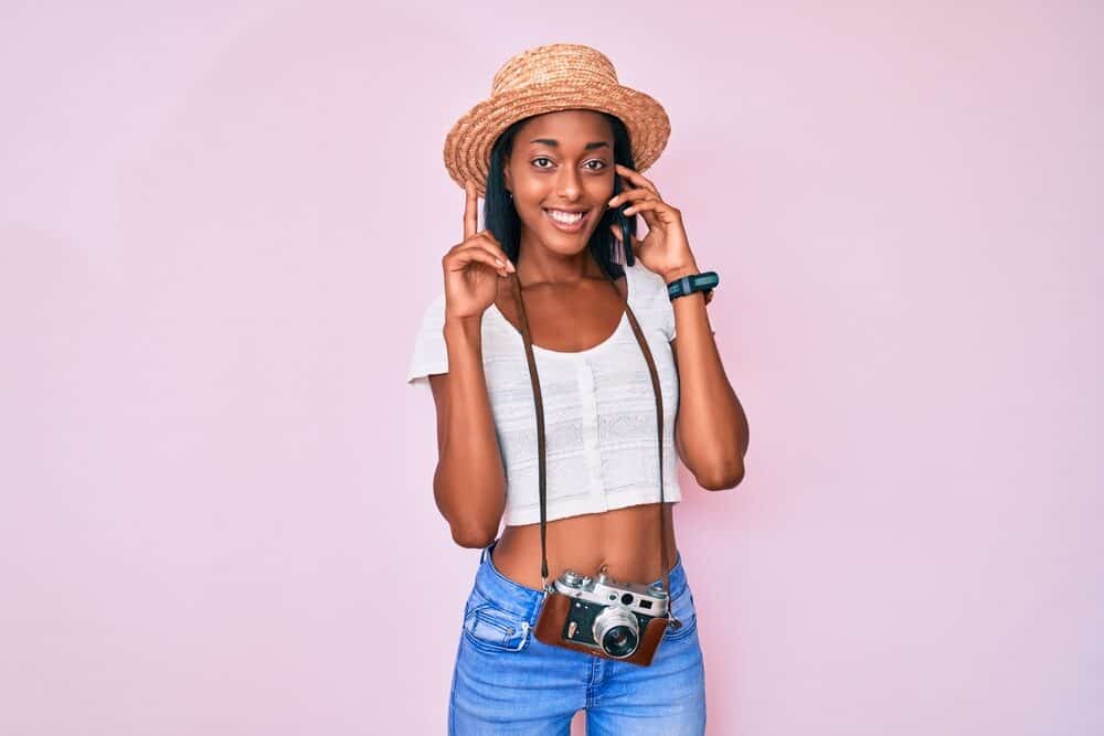 Cute African American girl talking on an iPhone while wearing a white shirt and blue jeans.