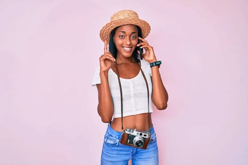 Best Steam Straighteners for Black, Curly, and Natural Hair 15 Cute African American girl talking on an iPhone while wearing a white shirt and blue jeans.