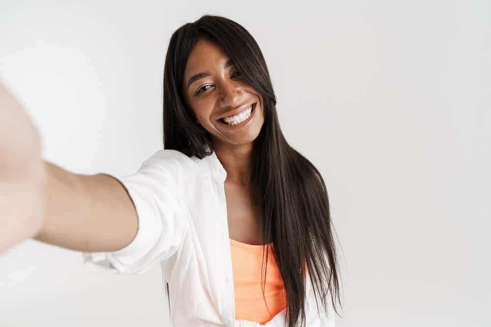 Pretty black woman wearing casual clothes and a good quality wig taking a selfie.