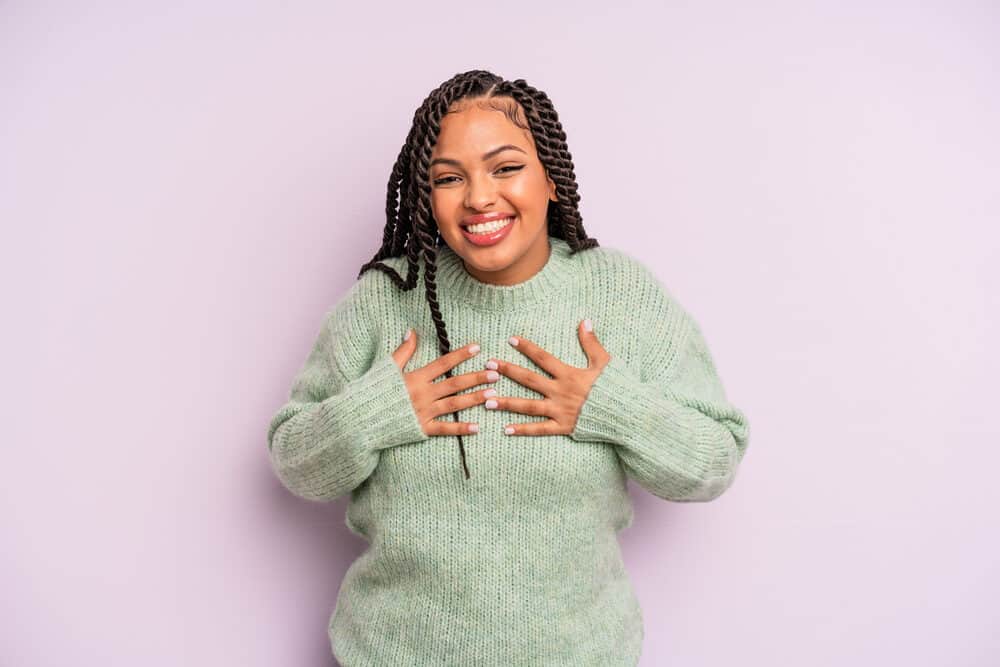 A female wearing Latina braids that could be adorned with faux flowers converted into two traditional low braids.