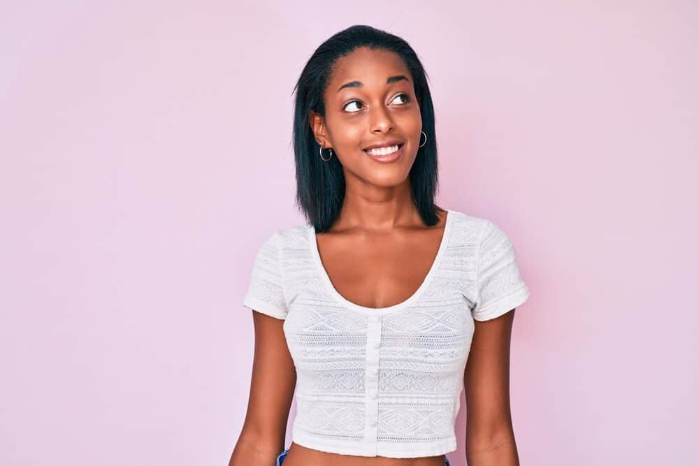 Young African American female with damaged hair cuticles after using a professional hair straightener with heat plates.