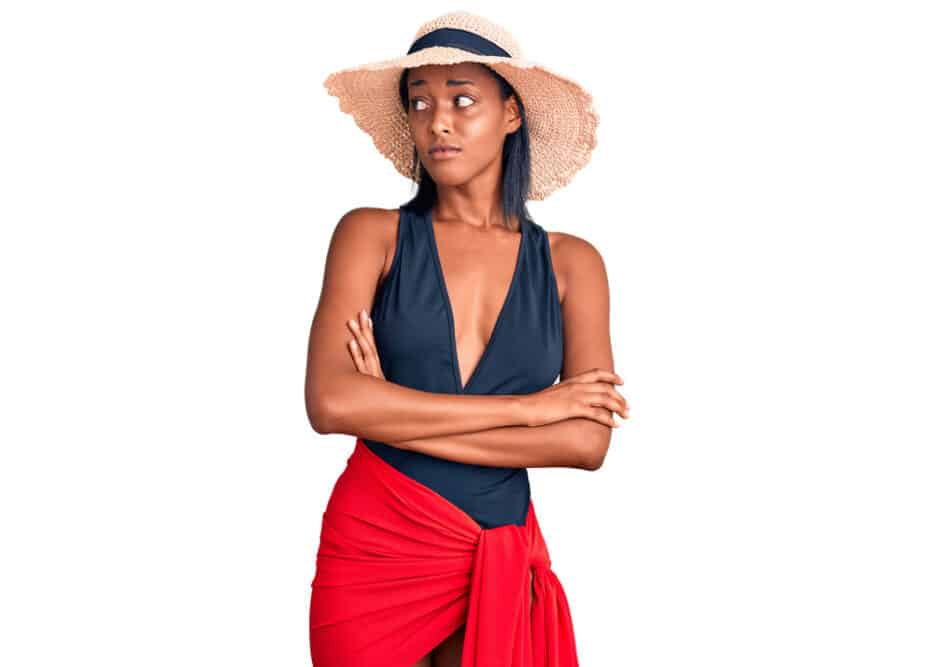 Young adult woman in tip-top shape wearing a straw hat as a protective style to prevent damage.