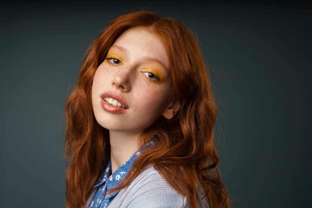 A young white woman with hair that's an orange color slightly lightened by the sun's UV light.