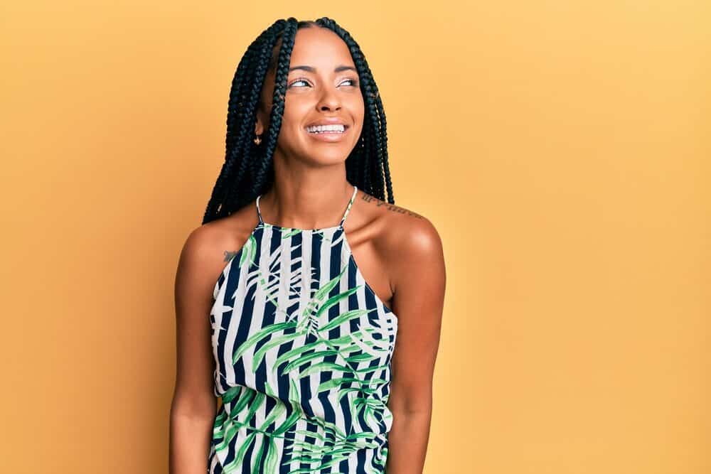 A beautiful Hispanic woman with a healthy hair canvas is wearing casual clothes and a braided protective hairdo.