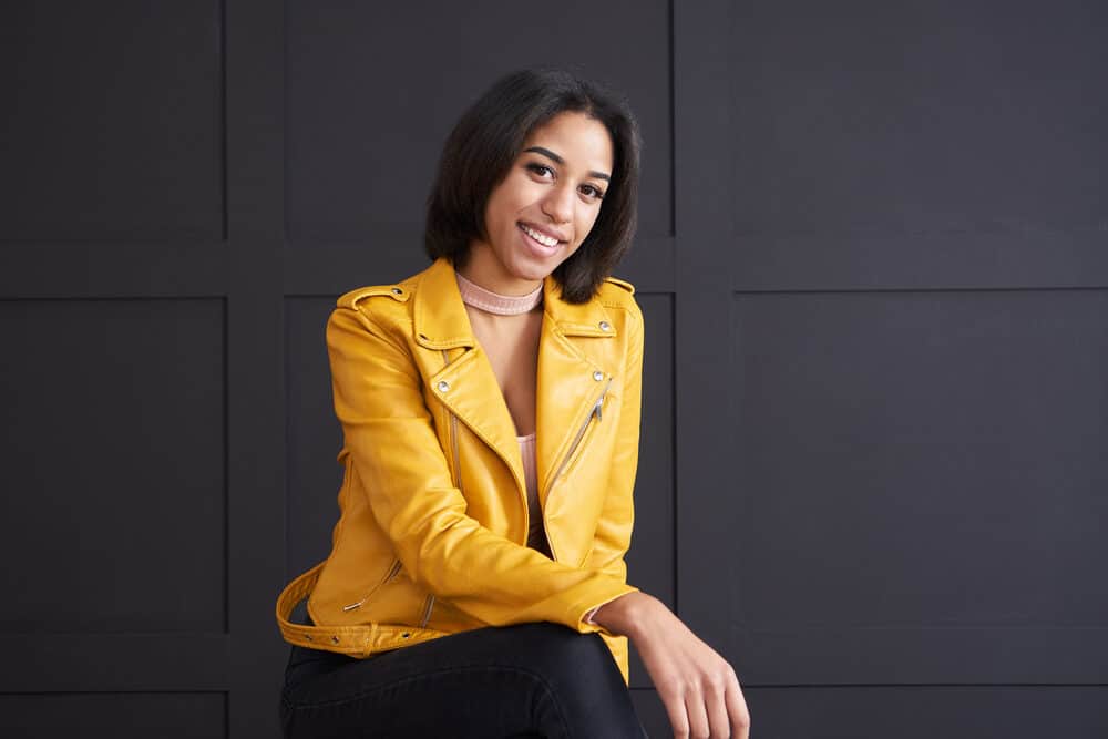 A fashionable young African female wearing a nice yellow jacket with brittle hair after overusing heat tools.