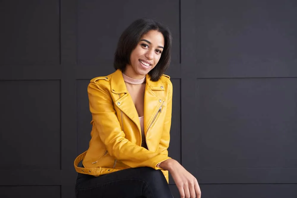 How Often Should You Flat Iron Your Hair (Without Damaging It) 6 A fashionable young African female wearing a nice yellow jacket with brittle hair after overusing heat tools.