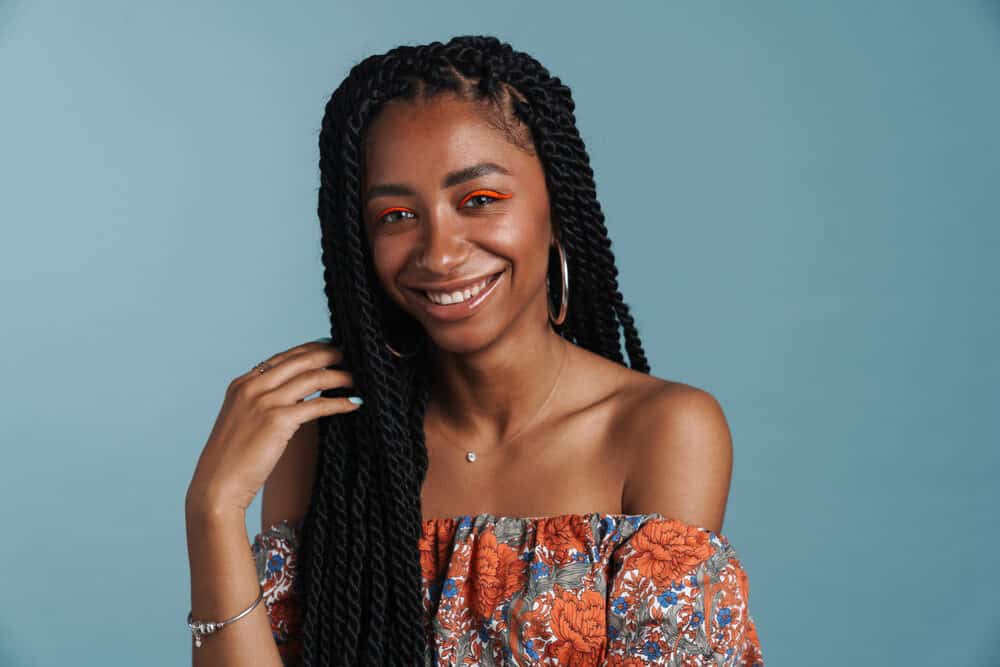 Young black woman with box braids wearing a casual outfit with blue fingernail polish.