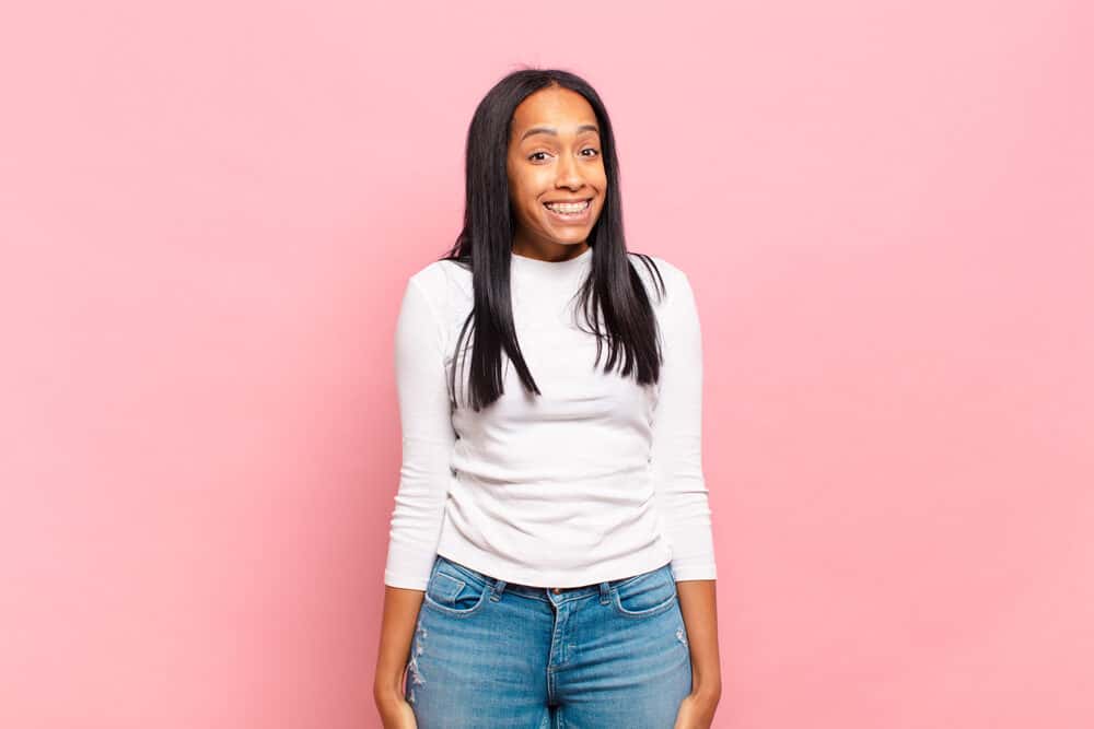 Adolescent black girl with a goofy smile wearing perfectly straight hair styled with a light hair spray.